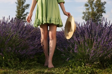 Photo of Woman with hat walking barefoot in lavender field, closeup