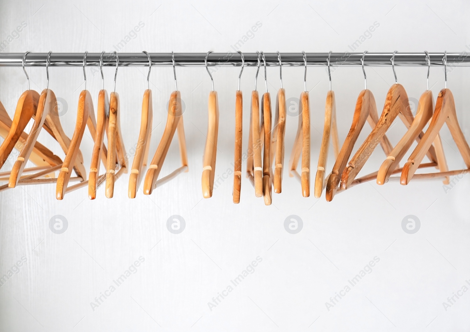 Photo of Clothes rail with wooden hangers on white background