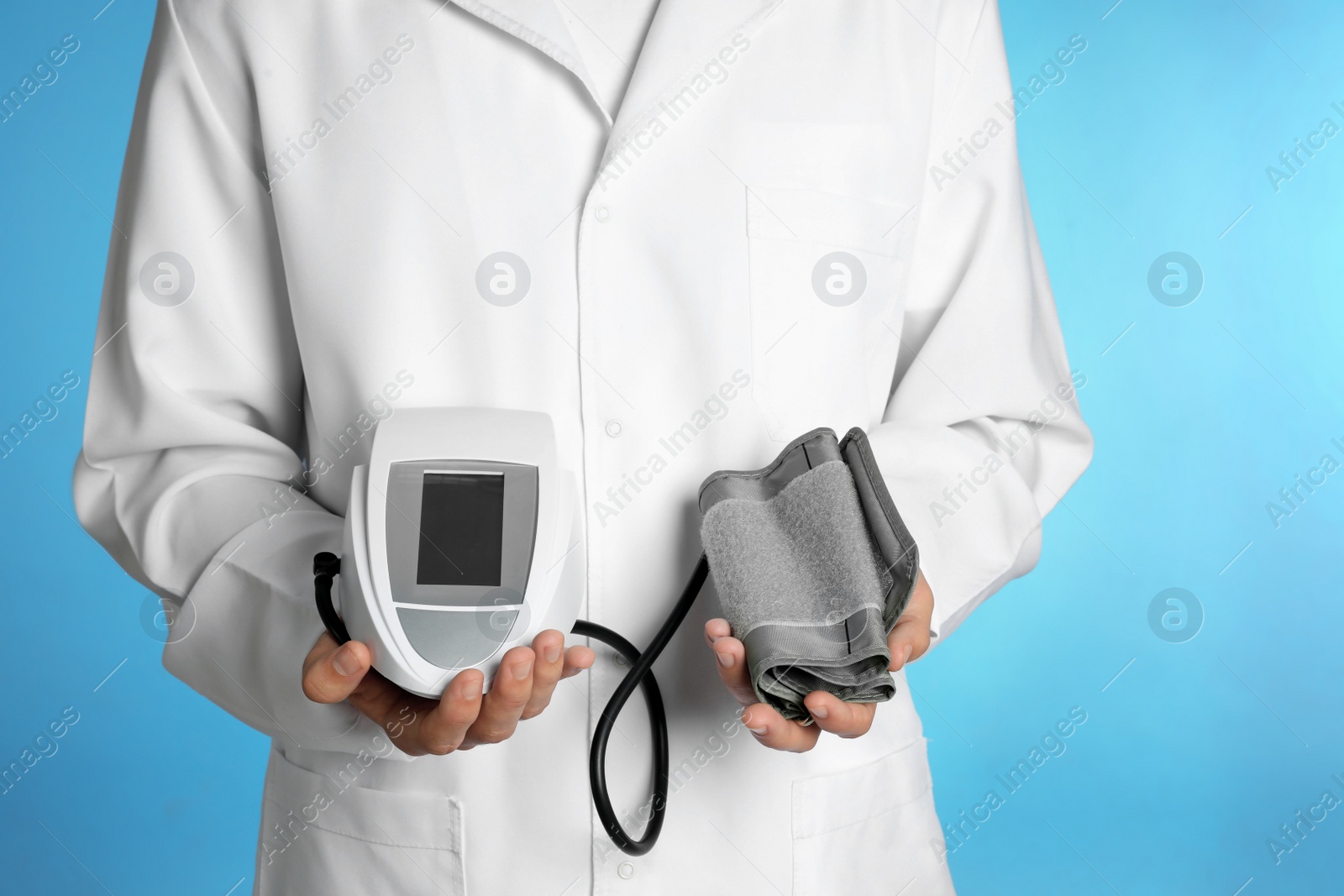 Photo of Male doctor holding blood pressure monitor on color background, closeup. Medical object