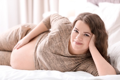 Young pregnant woman lying on bed at home