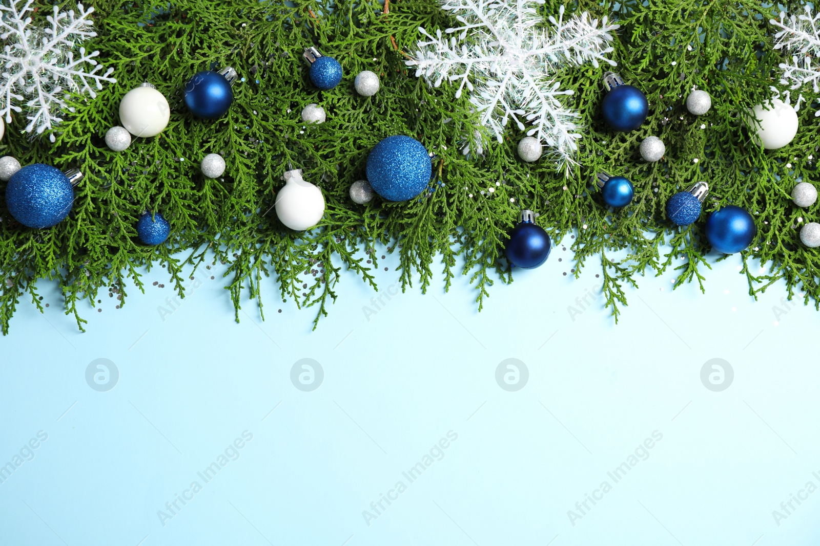 Photo of Fir tree branches with Christmas decoration on light blue background, flat lay. Space for text