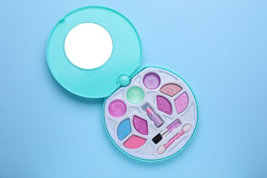 Photo of Decorative cosmetics for kids. Eye shadow palette with lipstick on light blue background, top view