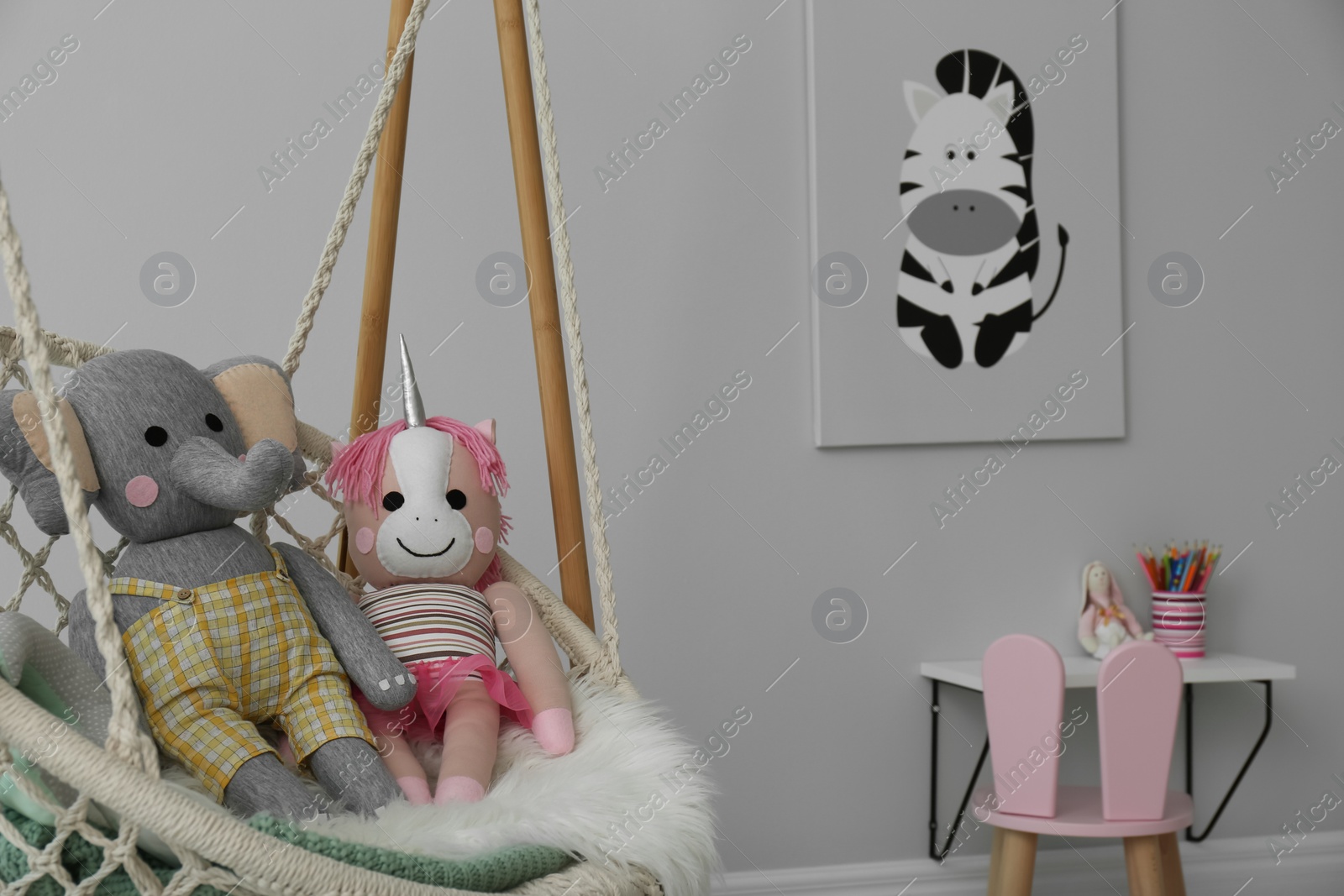 Photo of Stylish child's room interior with adorable painting and hanging chair