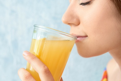 Photo of Young woman drinking lemon juice on color background, closeup
