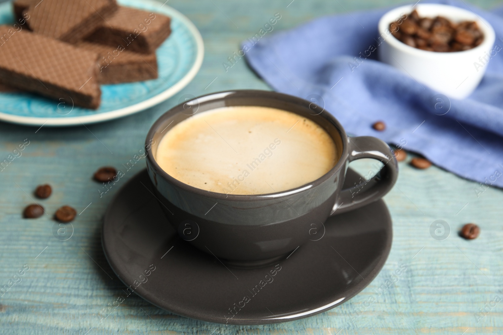 Photo of Delicious coffee and wafers for breakfast on light blue wooden table