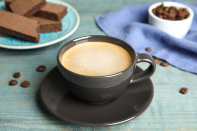 Photo of Delicious coffee and wafers for breakfast on light blue wooden table