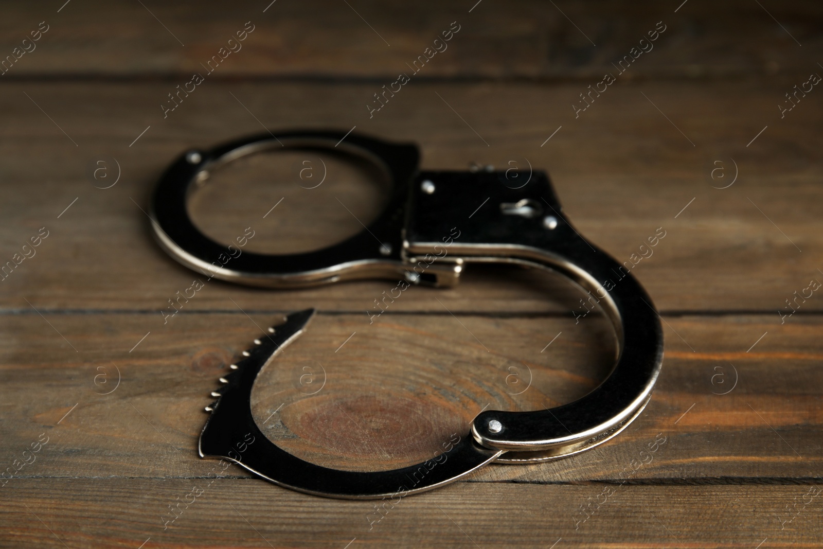 Photo of Classic chain handcuffs on wooden table, closeup