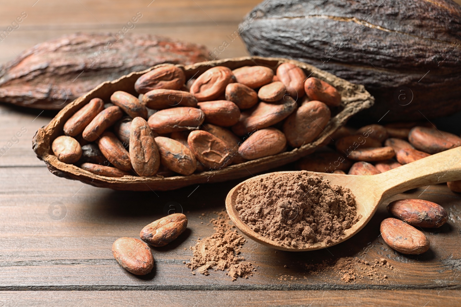 Photo of Composition with cocoa pods, beans and powder on wooden table