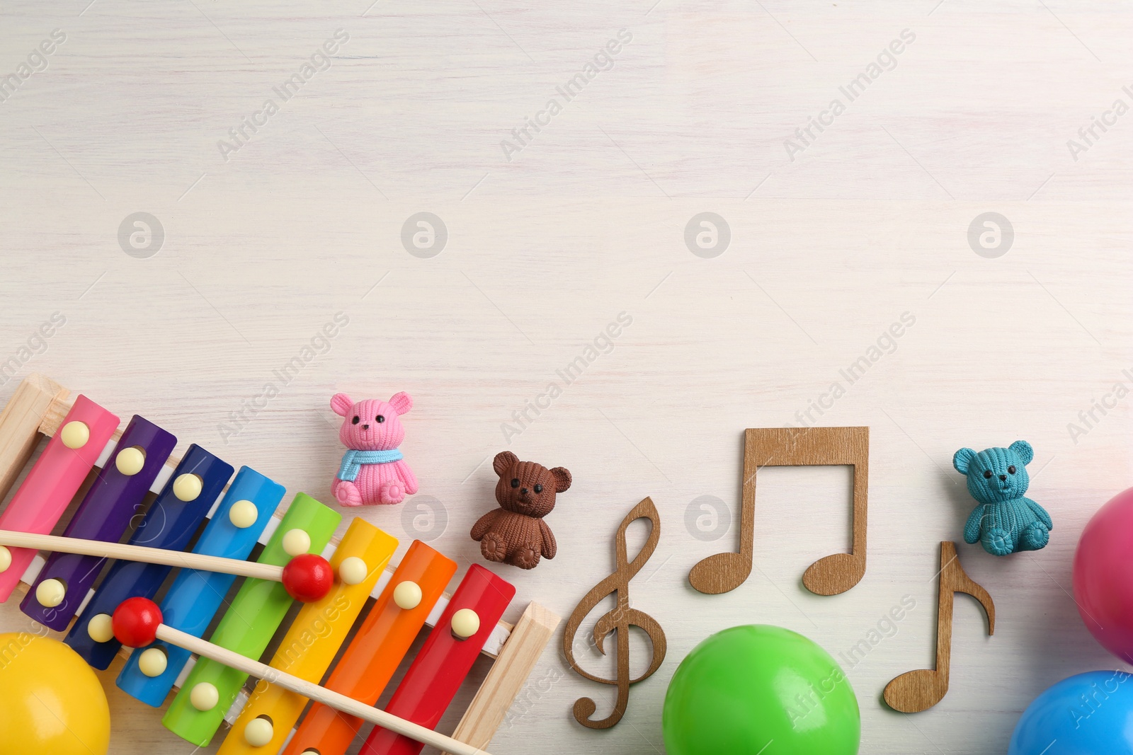 Photo of Baby song concept. Wooden notes, xylophone and toys on table, flat lay. Space for text