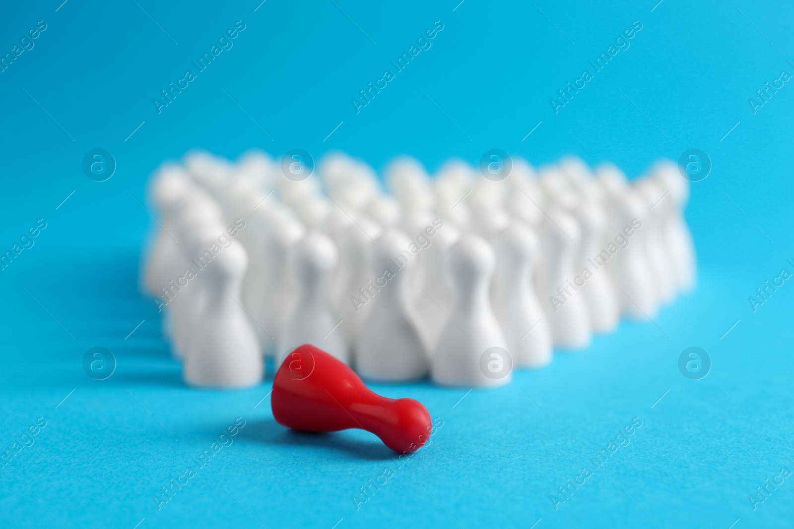 Photo of Fallen red pawn among others on light blue background, closeup. Social inclusion concept