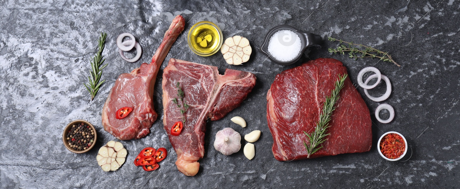 Photo of Fresh raw beef cuts and different spices on grey textured table, flat lay