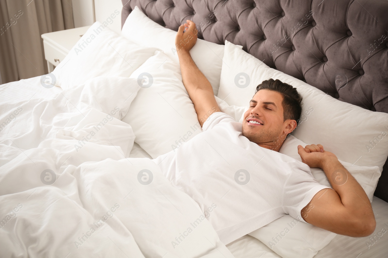 Photo of Man awakening on bed at home. Lazy morning