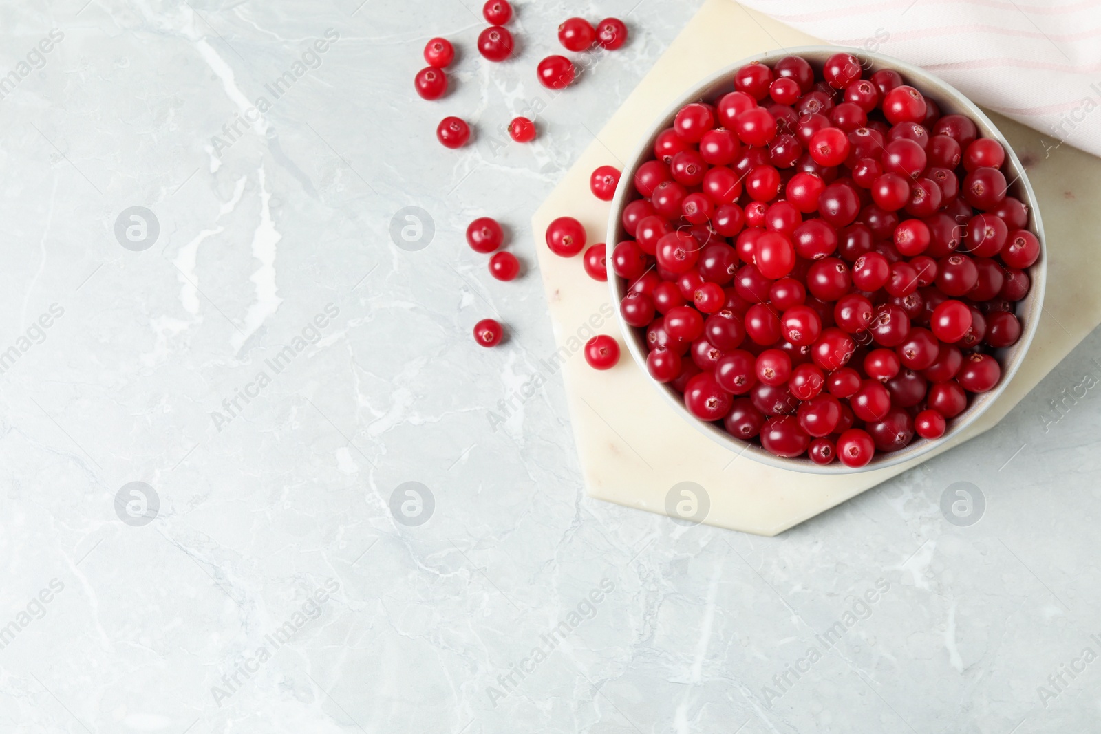 Photo of Tasty ripe cranberries on light grey marble table, flat lay. Space for text