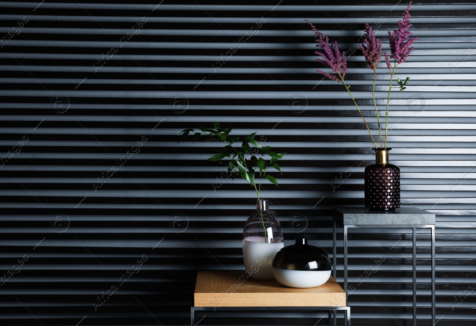 Photo of Stylish decorative vases with plants on stands