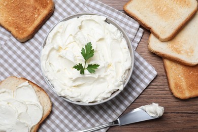 Toasted bread and delicious cream cheese with parsley on wooden table, flat lay