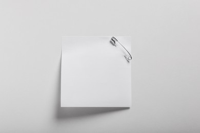 Photo of Paper note attached with safety pin on white background