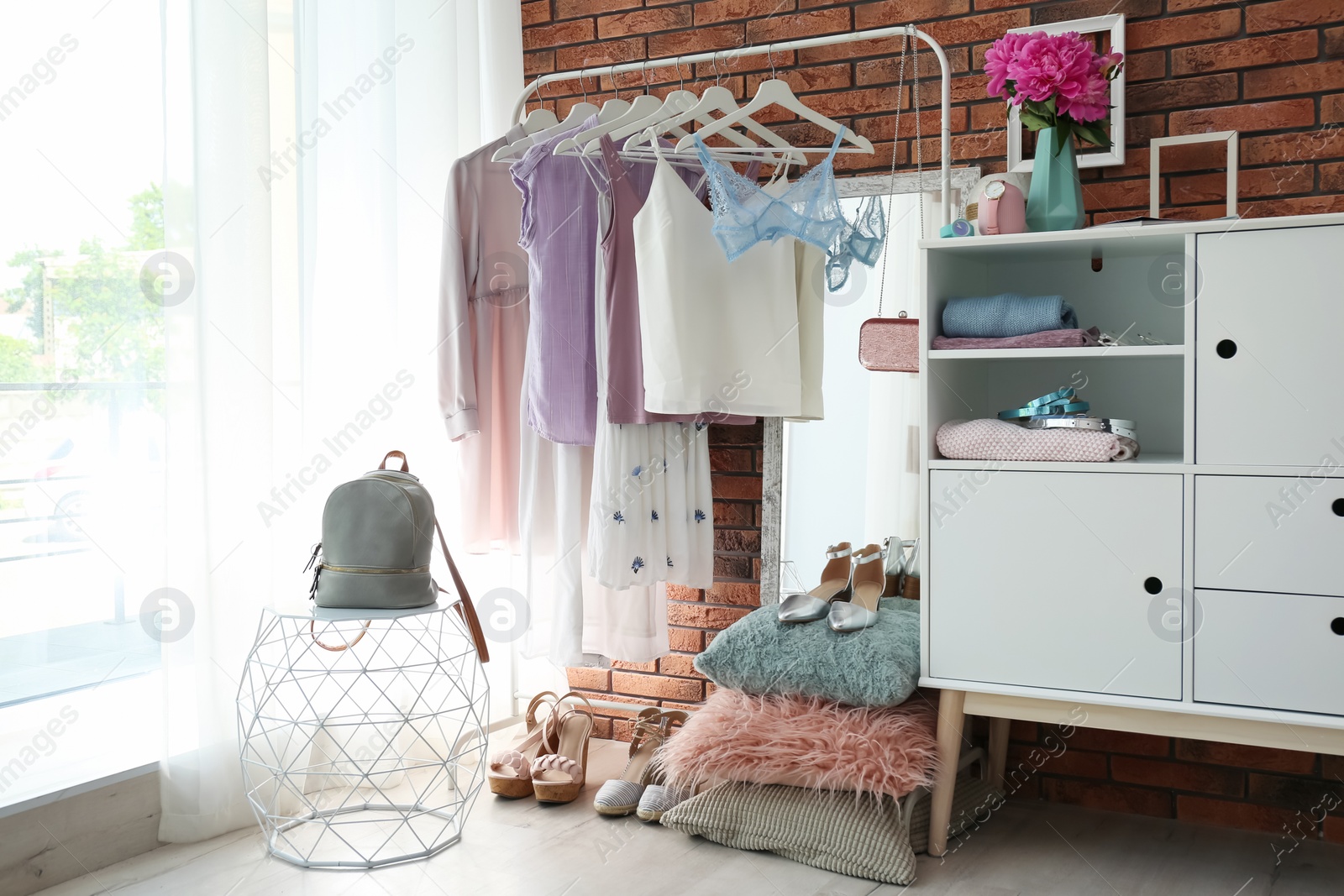 Photo of Stylish dressing room interior with clothes on rack