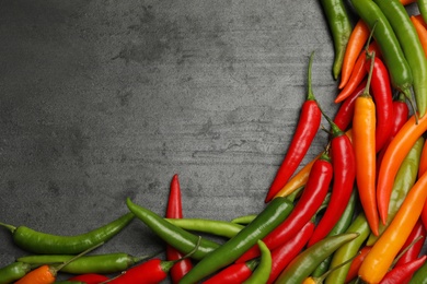 Photo of Different ripe chili peppers grey table, flat lay. Space for text