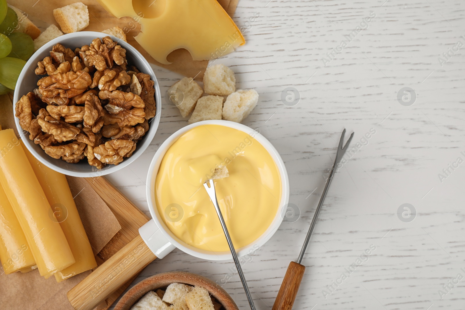 Photo of Flat lay composition with pot of tasty cheese fondue and products on white wooden table