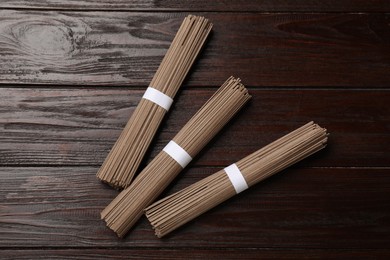 Photo of Uncooked buckwheat noodles (soba) on wooden table, flat lay