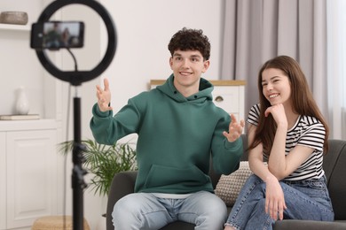 Photo of Smiling teenage bloggers talking while streaming at home