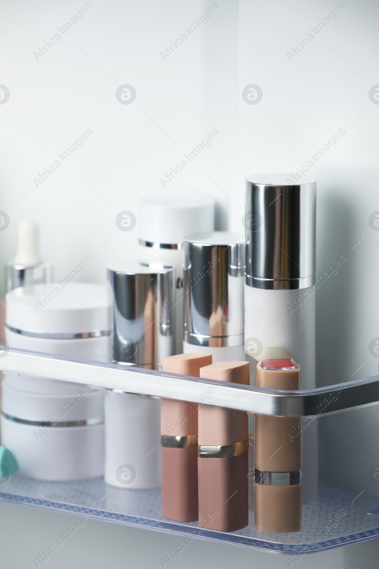 Photo of Different cosmetic products on shelf in refrigerator