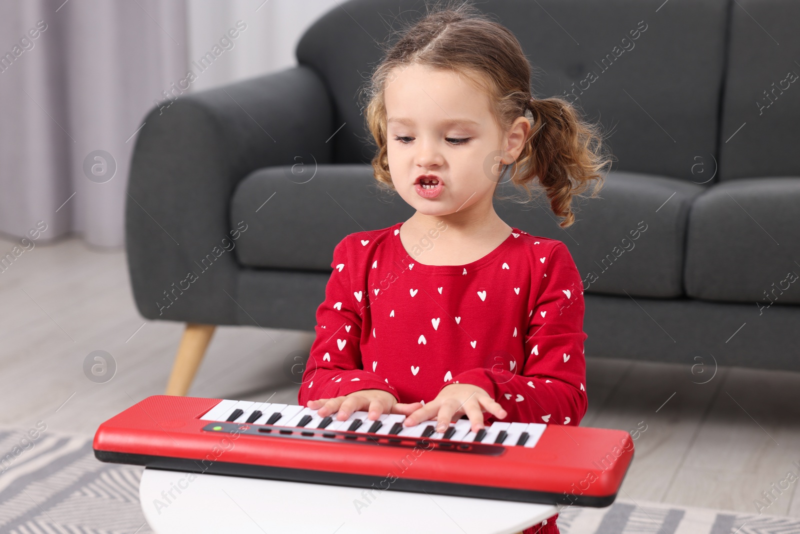 Photo of Little girl playing toy piano at home