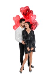 Photo of Happy young couple with heart shaped balloons isolated on white. Valentine's day celebration