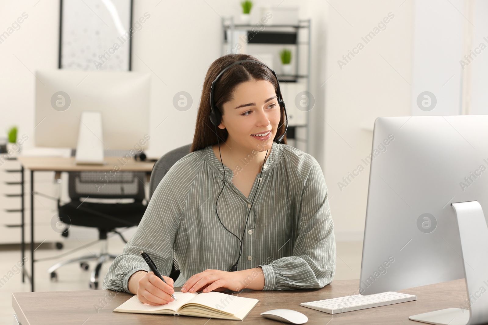 Photo of Hotline operator with headset working on computer in office