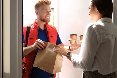 Courier giving order to young woman at open door. Food delivery service