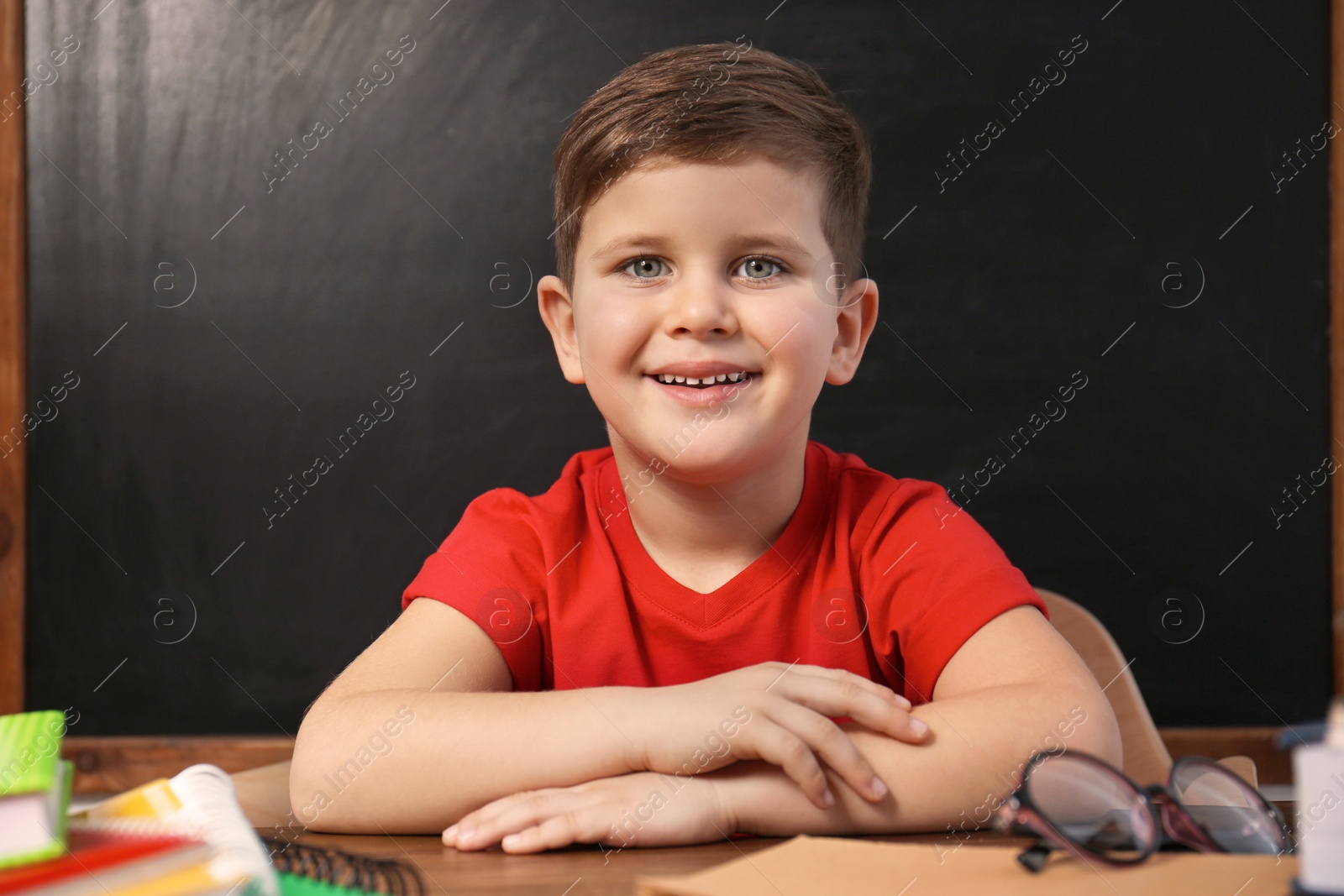 Photo of Cute little child at desk in classroom. First time at school