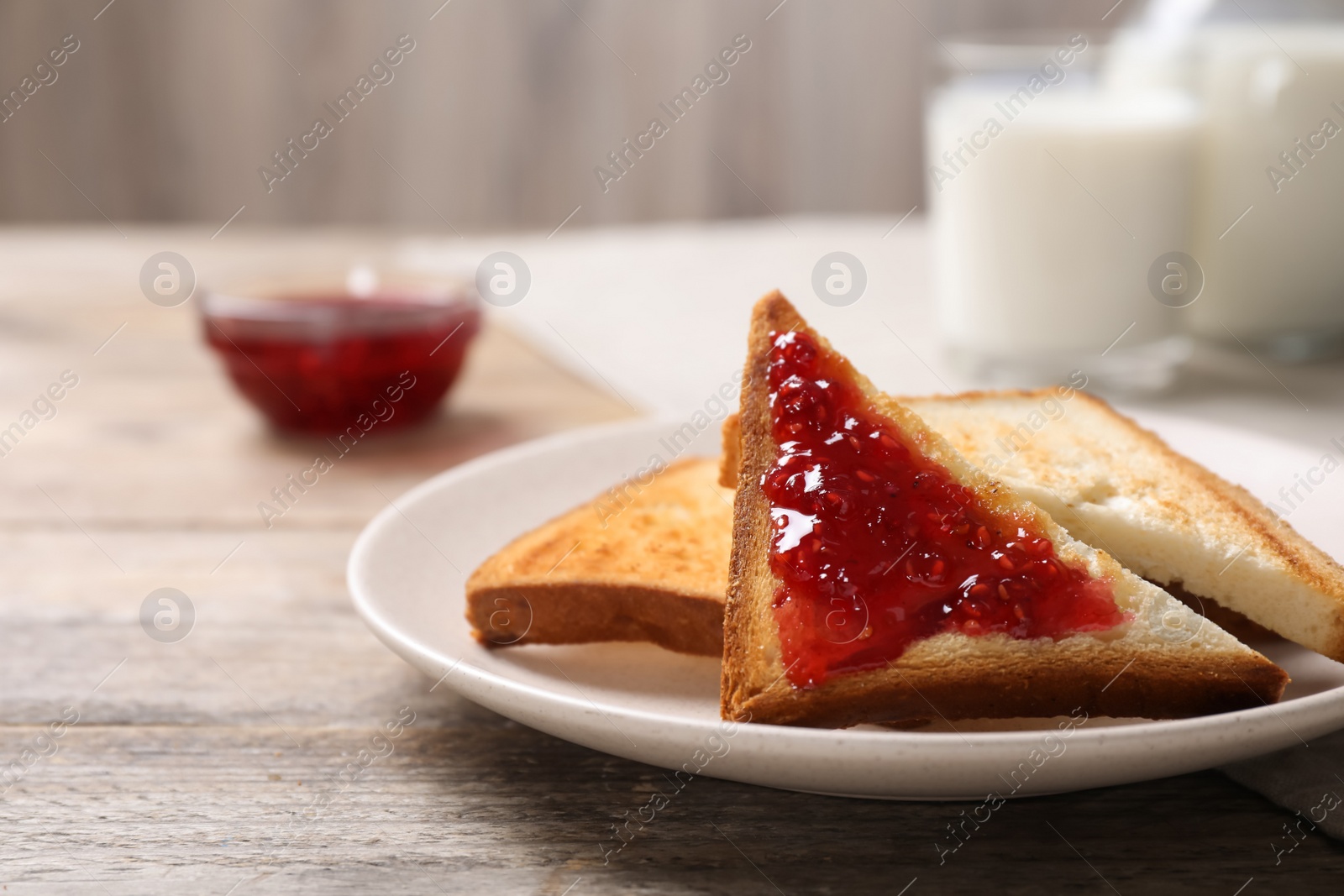 Photo of Tasty toasts with jam served for breakfast on wooden table