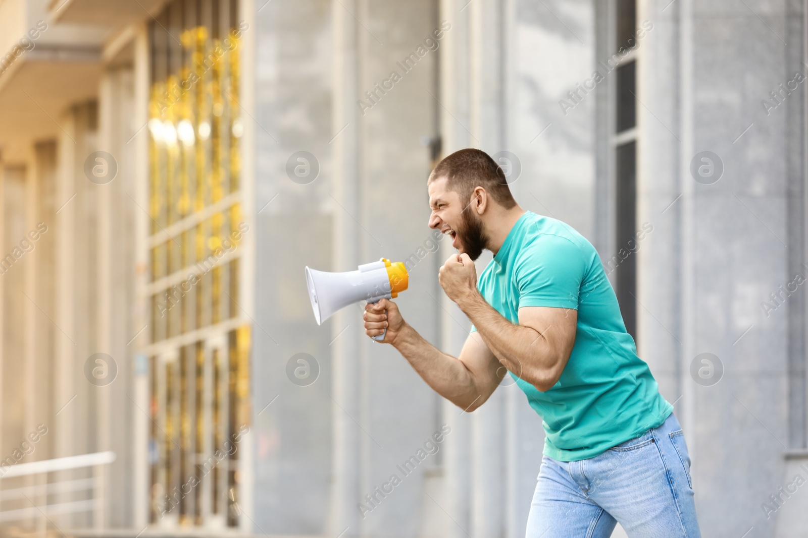 Image of Emotional young man with megaphone outdoors. Protest leader