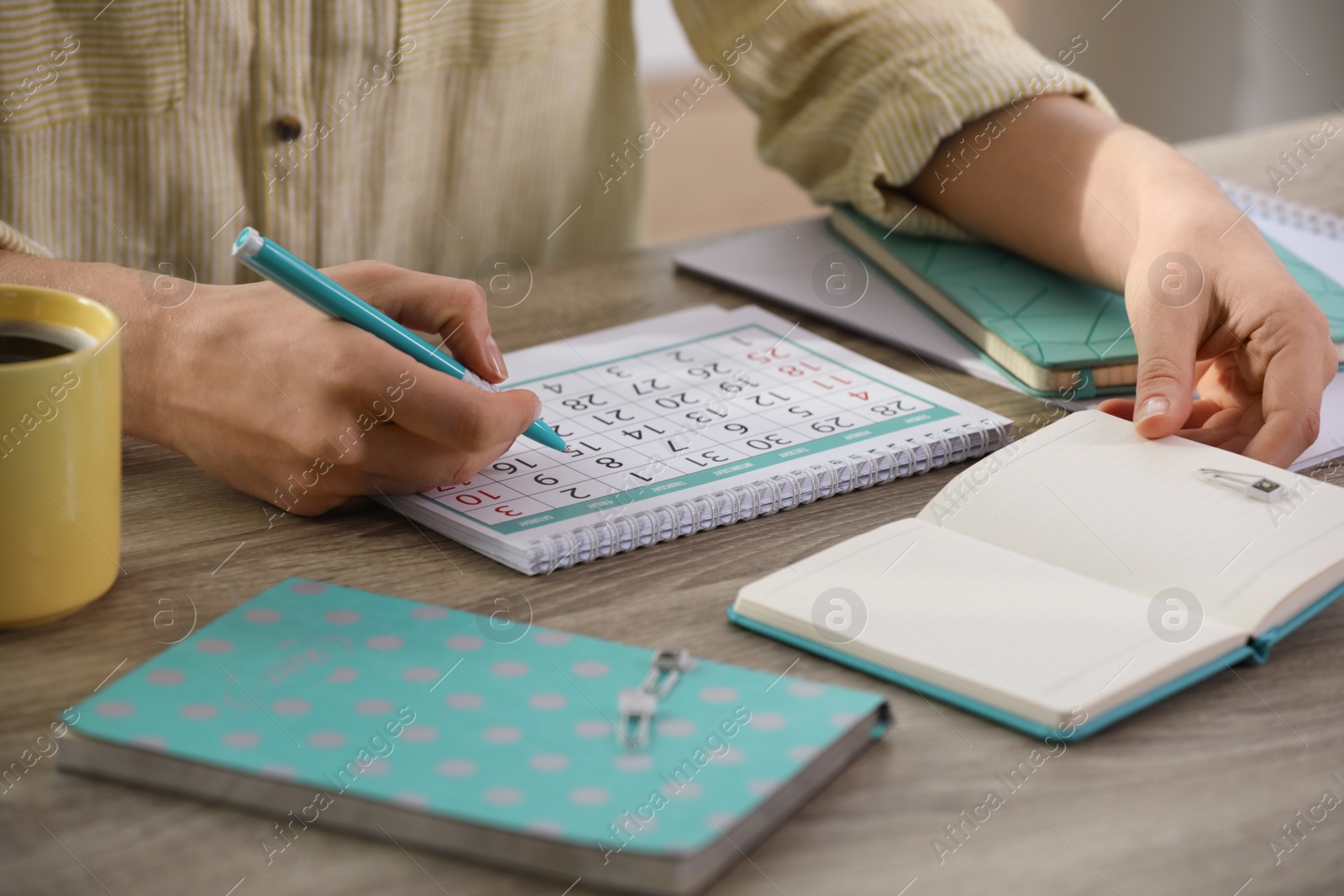 Photo of Woman making schedule using calendar at wooden table, closeup