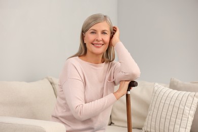 Photo of Mature woman with walking cane on sofa indoors