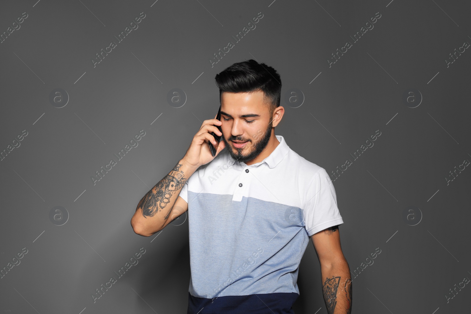 Photo of Portrait of handsome young man with mobile phone on gray background