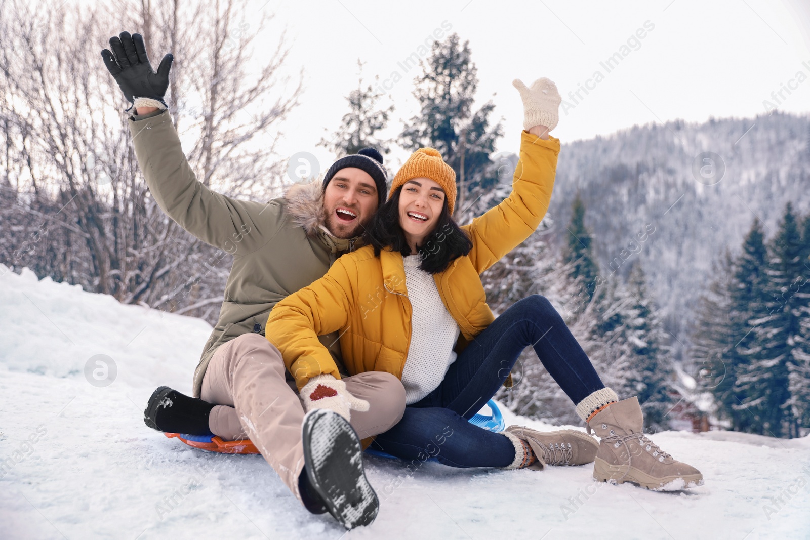 Photo of Happy couple sliding on snowy hill. Winter vacation