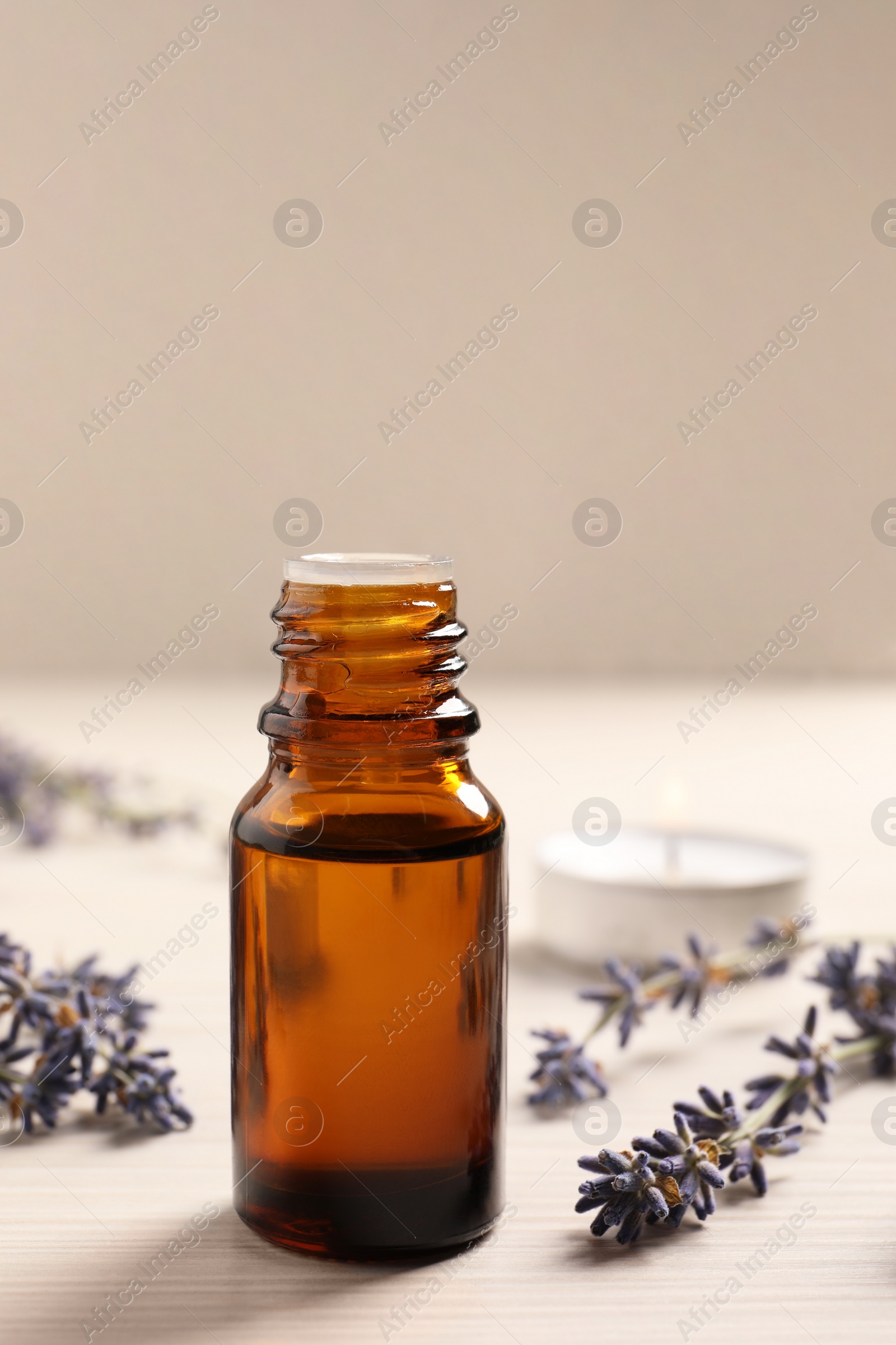 Photo of Bottle of essential oil and lavender flowers on white wooden table, closeup