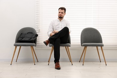 Photo of Man sitting on chair and waiting for job interview indoors