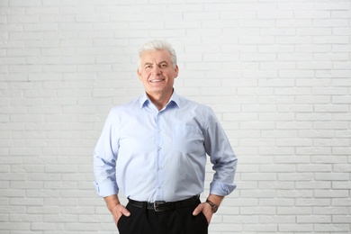 Portrait of handsome mature man near brick wall