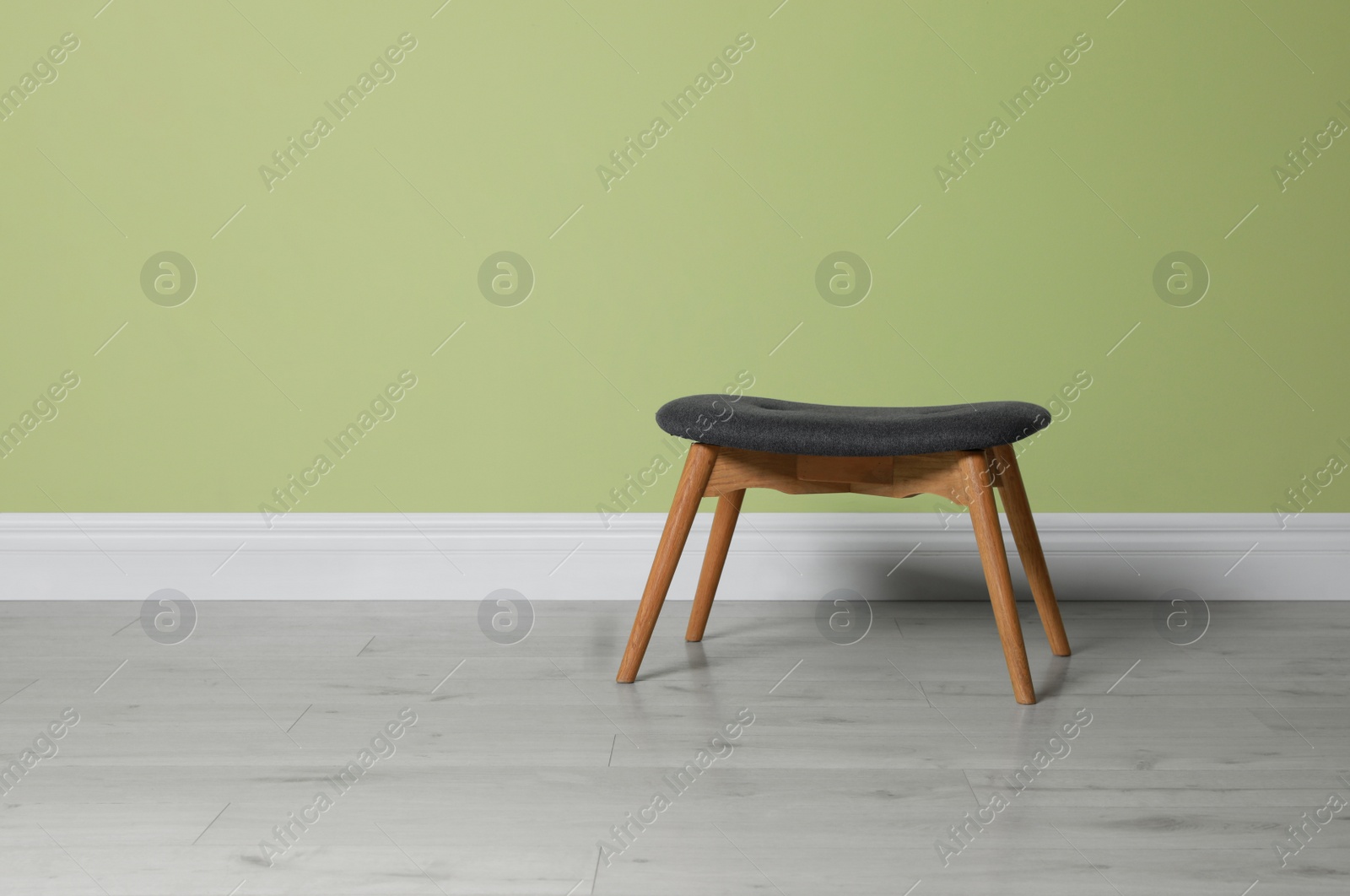 Photo of Stylish stool near light green wall indoors. Space for text