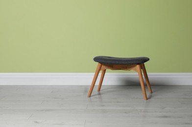 Photo of Stylish stool near light green wall indoors. Space for text