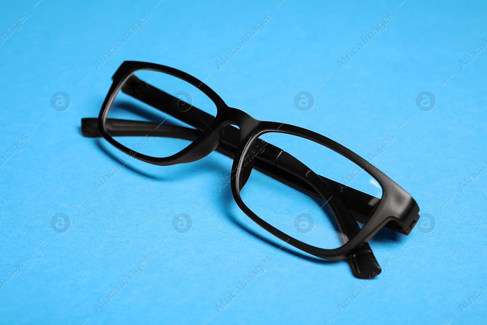 Photo of Glasses in stylish frame on light blue background
