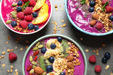 Image of Delicious acai smoothie with toppings in bowls on table, flat lay