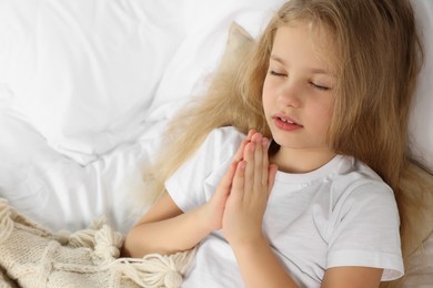 Photo of Girl with clasped hands praying in bed
