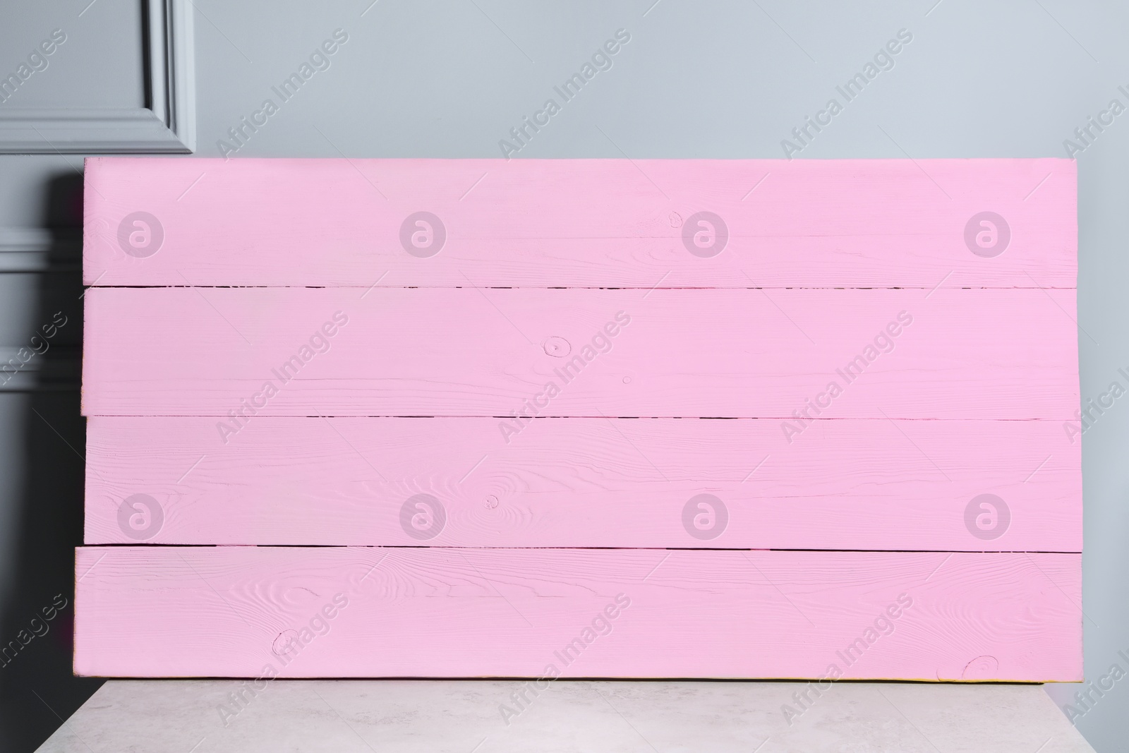 Photo of Pink wooden board on table near light grey wall