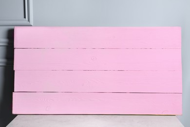 Photo of Pink wooden board on table near light grey wall