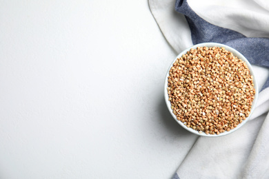 Bowl with green buckwheat on white table, top view. Space for text