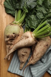 Photo of Fresh sugar beets with leaves on wooden table, flat lay