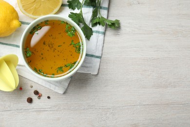 Photo of Bowl of lemon sauce and ingredients on white wooden table, flat lay with space for text. Delicious salad dressing